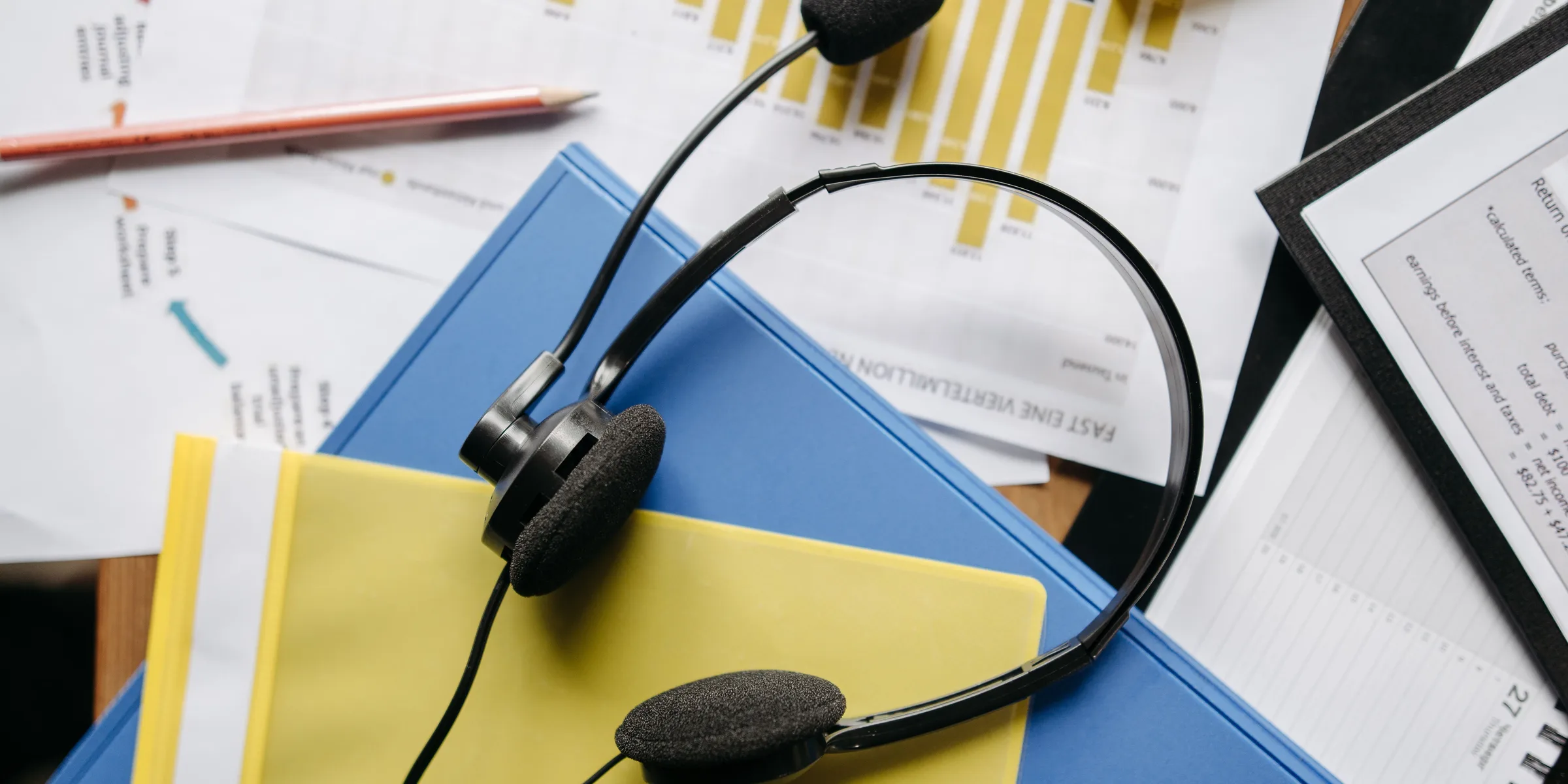A call center headset lying on folders and printed charts