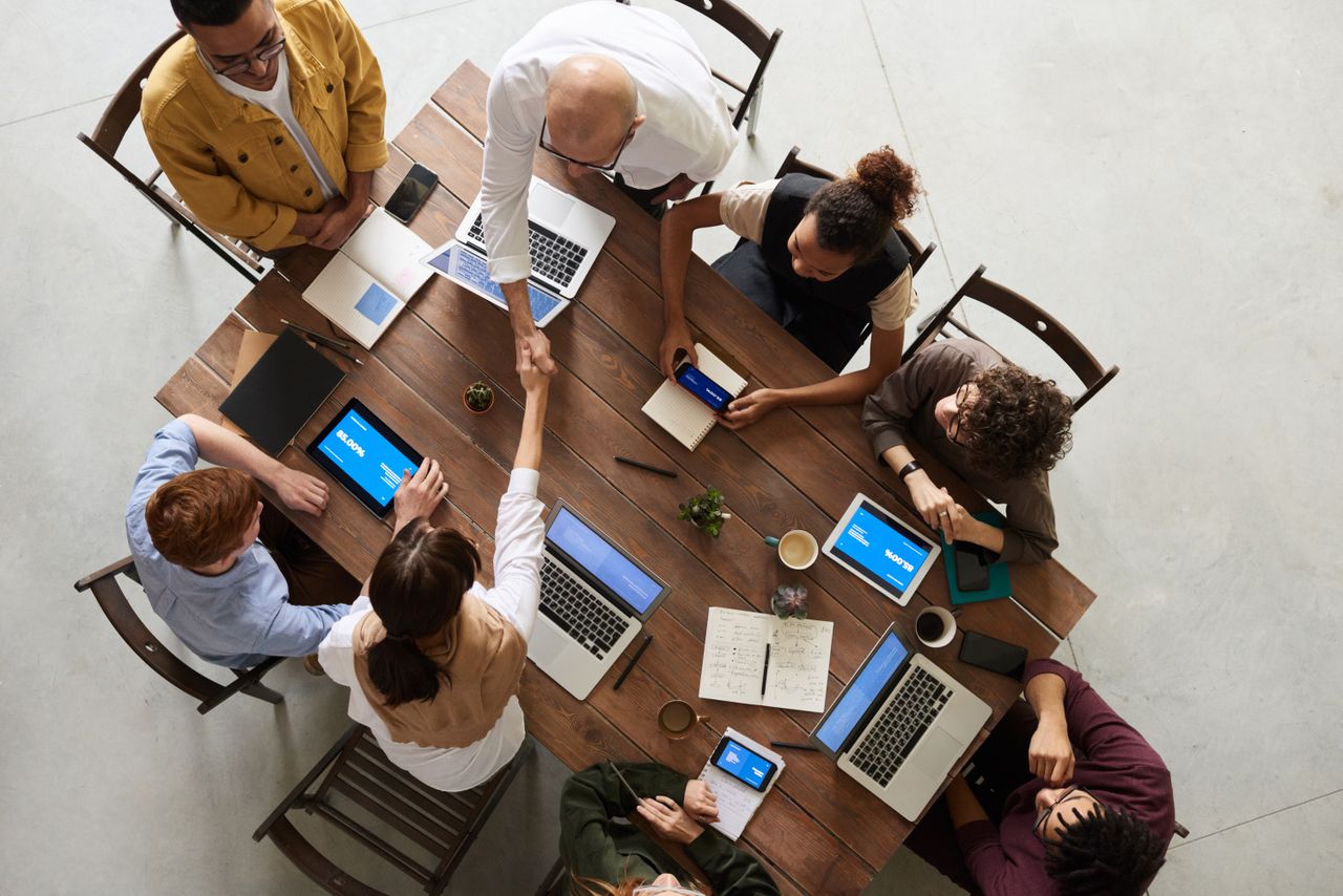 A diverse team collaborating around a table full of laptops, representing PowerOffice Go cloud ERP users